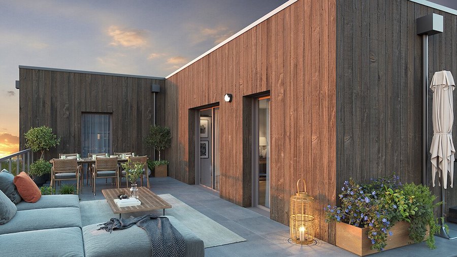 Vaste terrasse en attique aménagée avec salon de jardin et coin repas, bordée par des murs en bardage bois chaleureux au coucher du soleil